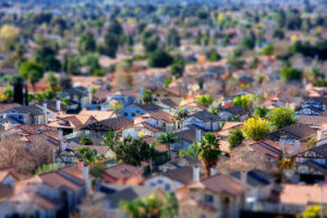 Imagem aérea de casas em uma cidade de interior, com menos prédios e muitas árvores