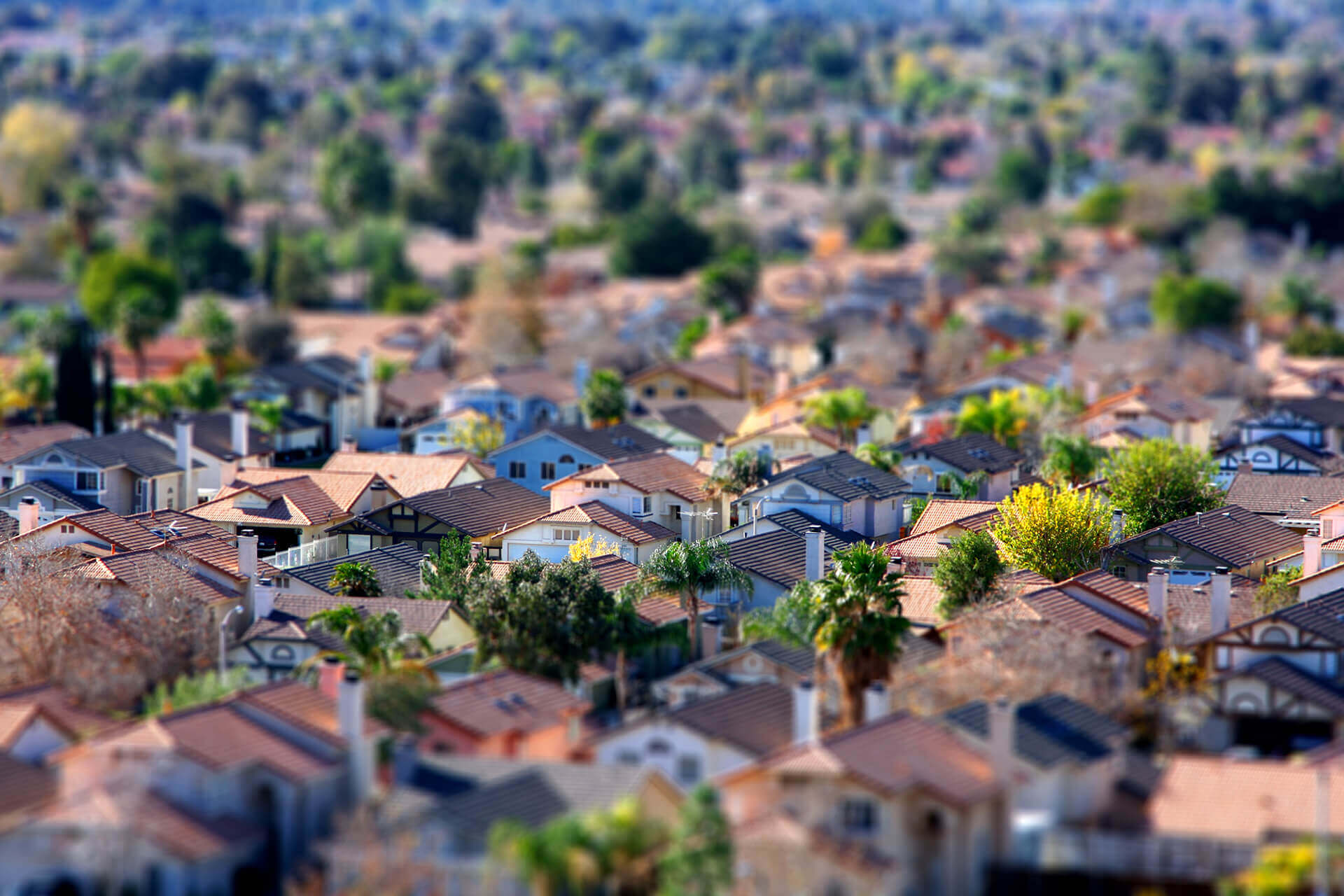 Imagem aérea de casas em uma cidade de interior, com menos prédios e muitas árvores